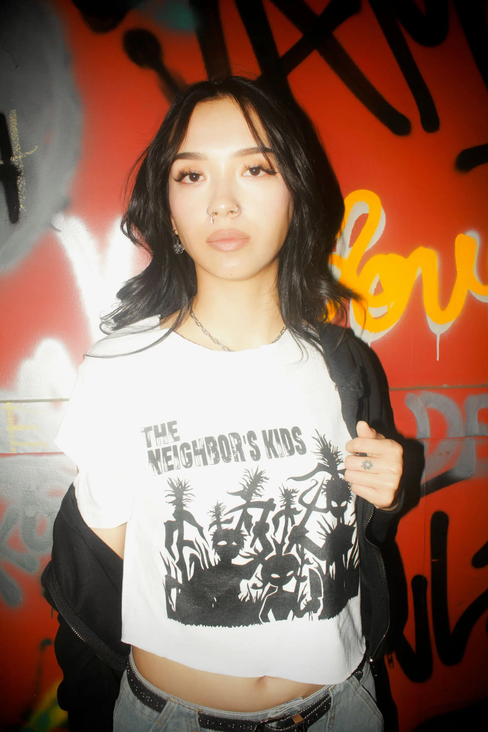 Model against a graffiti wall in the white logo tee