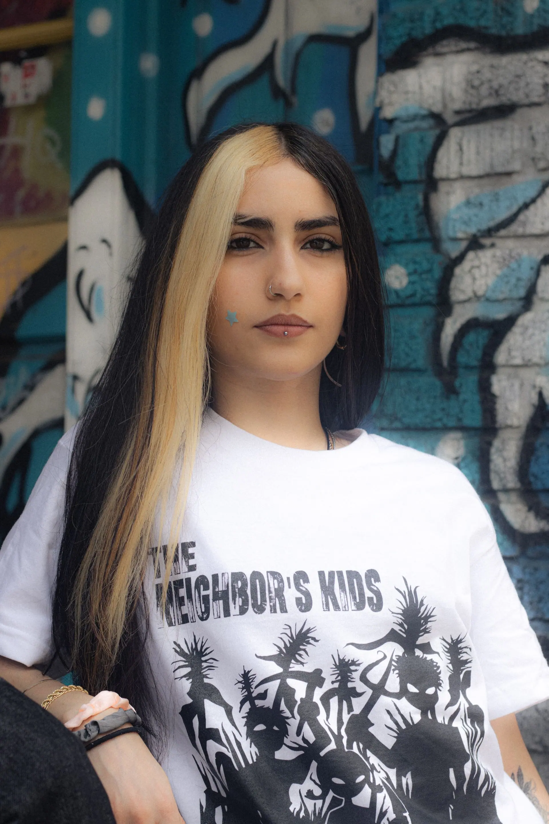 Model on a brick ledge in the white logo tee